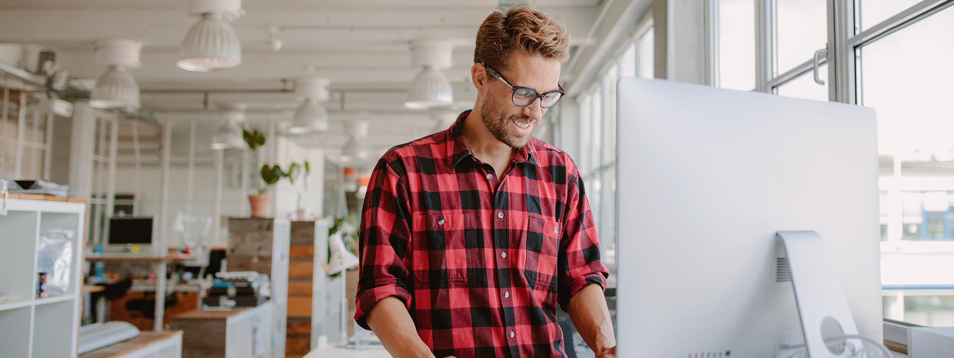 Man smiling in front of his computer monitor